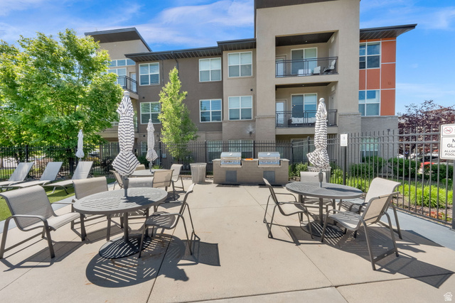 7713 Navarro View Court Midvale, UT 84047 - Photo 33 of 41 Outdoor patio area featuring multiple dining tables with umbrellas, lounge seating, a barbecue station with two grills, and a black metal fence