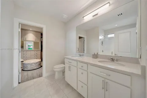 a spacious bathroom with a double vanity sink a toilet and a mirror
