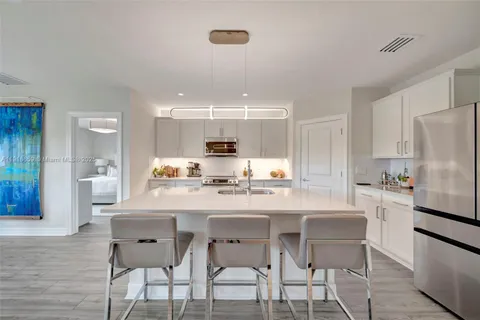 a kitchen with a dining table chairs refrigerator and cabinets