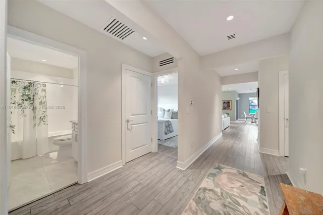 a view of a hallway with wooden floor and a bathroom