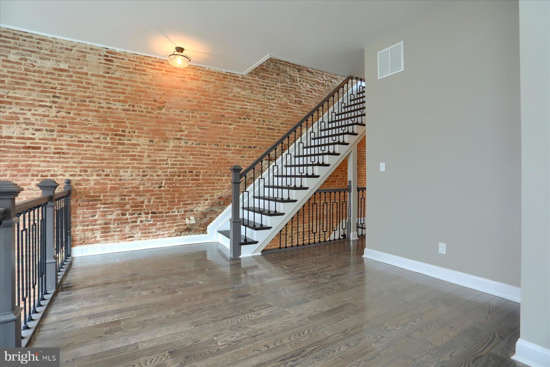 1811 Madison Avenue Baltimore, MD 21217 - Photo 15 of 37 a view of an empty room with wooden floor and stairs