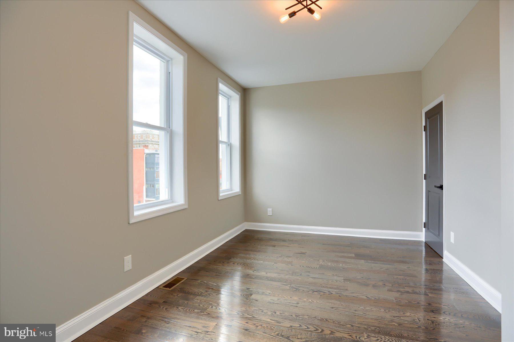 1811 Madison Avenue Baltimore, MD 21217 - Photo 27 of 37 an empty room with wooden floor and windows