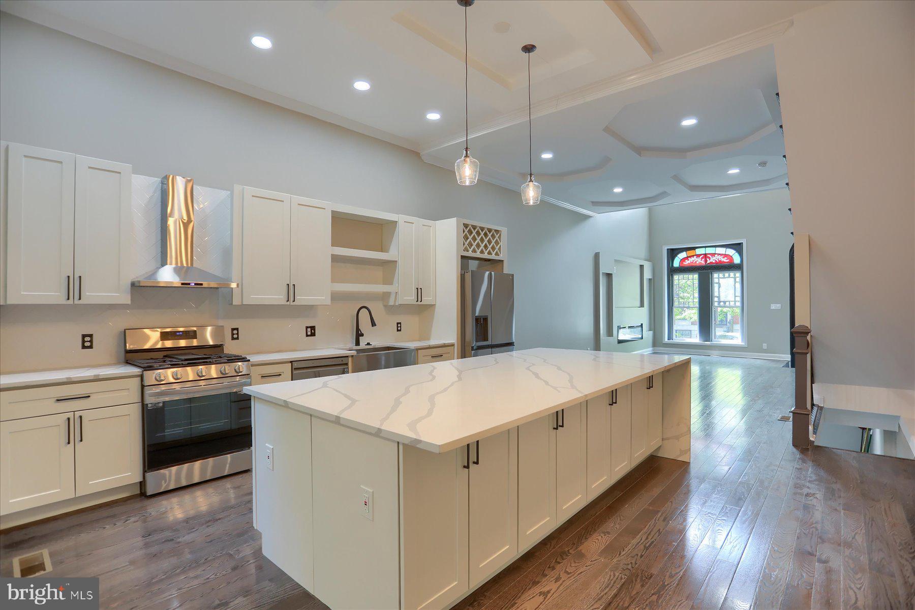 1811 Madison Avenue Baltimore, MD 21217 - Photo 9 of 37 a large white kitchen with lots of counter space wooden floor and stainless steel appliances