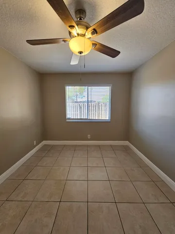a view of an empty room and chandelier fan