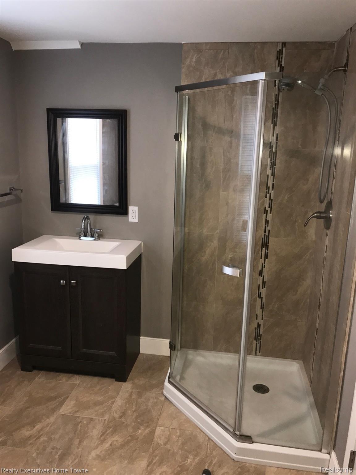 2427 Cambridge Road Berkley, MI 48072 - Photo 14 of 17 Corner glass-enclosed shower with tile surround and decorative vertical accent