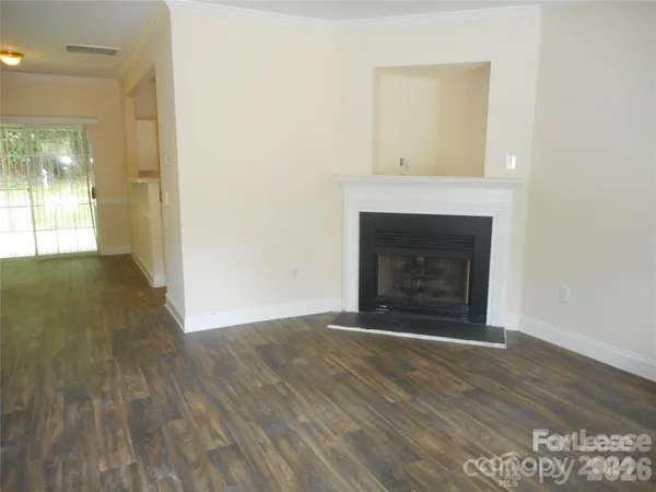 a view of an empty room with wooden floor and a fireplace