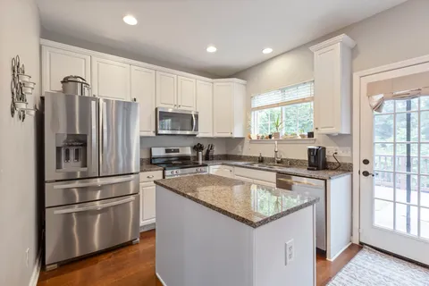 a kitchen with stainless steel appliances granite countertop a refrigerator a sink a stove a microwave and island