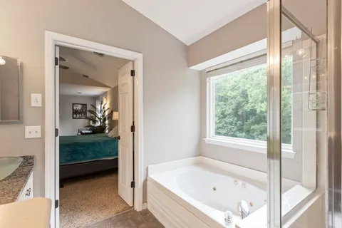 a en suite bathroom with a granite countertop tub sink and mirror