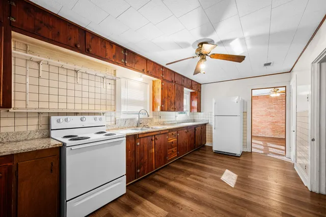 a kitchen that has a lot of cabinets in it and wooden floor