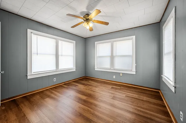 a view of an empty room with window and wooden floor
