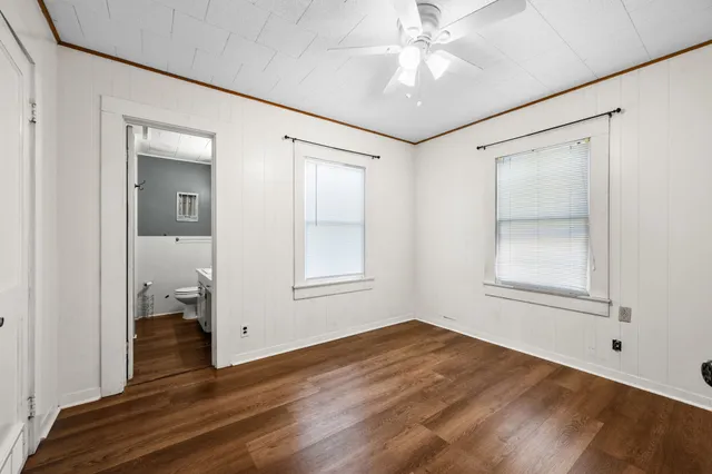 a view of empty room with wooden floor and fan