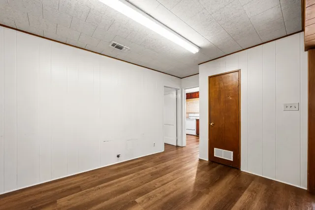 a view of an empty room with wooden floor and closet