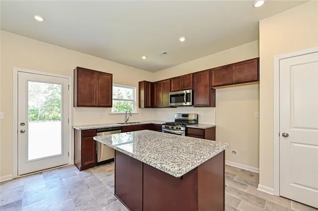 a kitchen with stainless steel appliances granite countertop a refrigerator a sink a stove a microwave and island