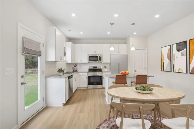 a kitchen with a sink a stove a refrigerator and a dining table with wooden floor