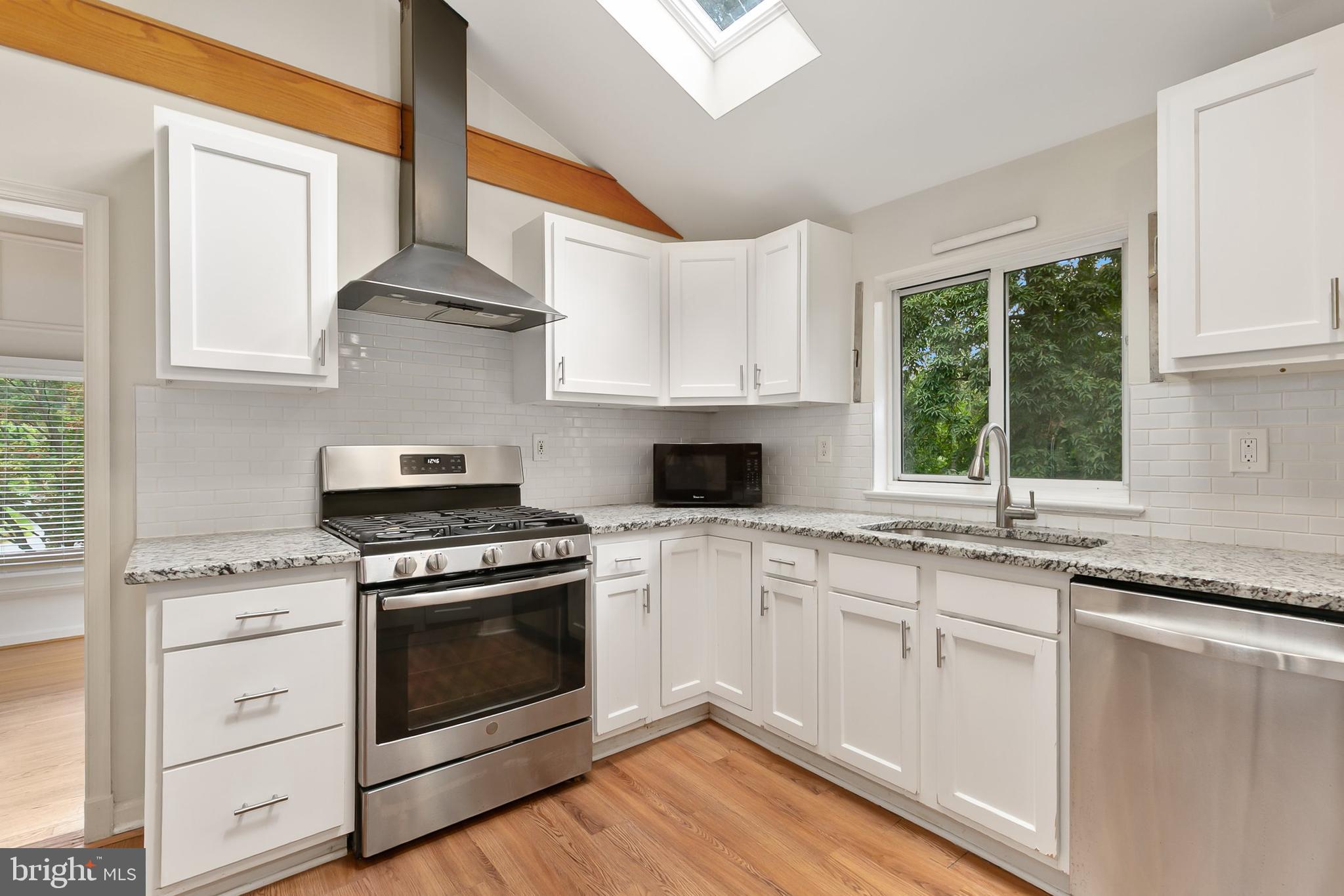 10601 Kinloch Road Silver Spring, MD 20903 - Photo 15 of 47 a kitchen with stainless steel appliances granite countertop white cabinets a stove a sink and a window