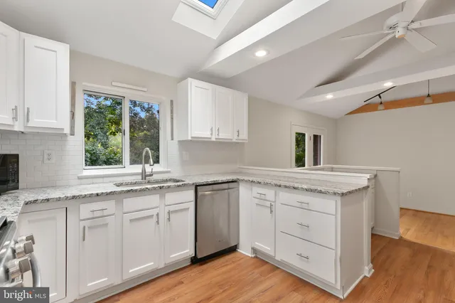 a kitchen with white cabinets and a window