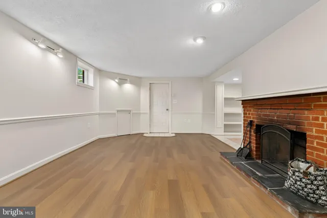 a view of empty room with wooden floor and fireplace