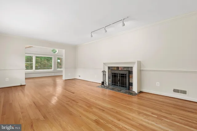 an empty room with wooden floor fireplace and windows