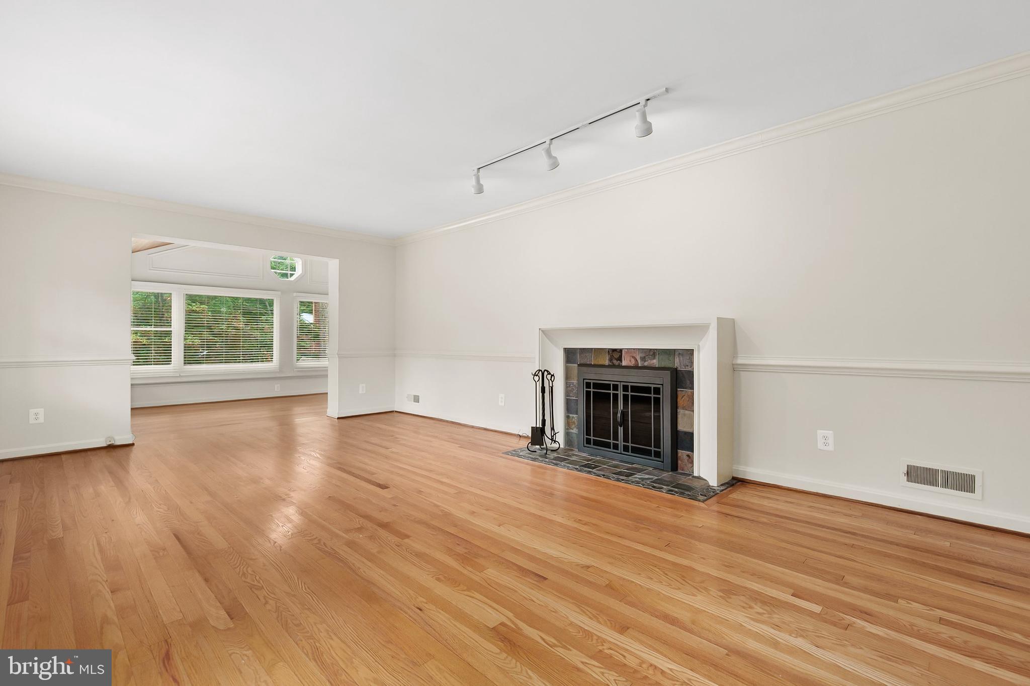 10601 Kinloch Road Silver Spring, MD 20903 - Photo 7 of 47 an empty room with wooden floor fireplace and windows