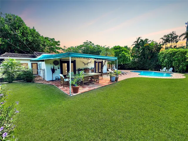 a view of patio with table and chairs potted plants and large tree