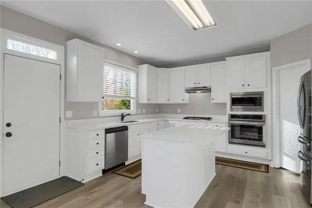 a kitchen with a sink white cabinets and white appliances