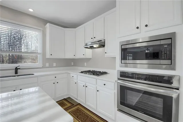 a kitchen with stainless steel appliances white cabinets and a stove top oven