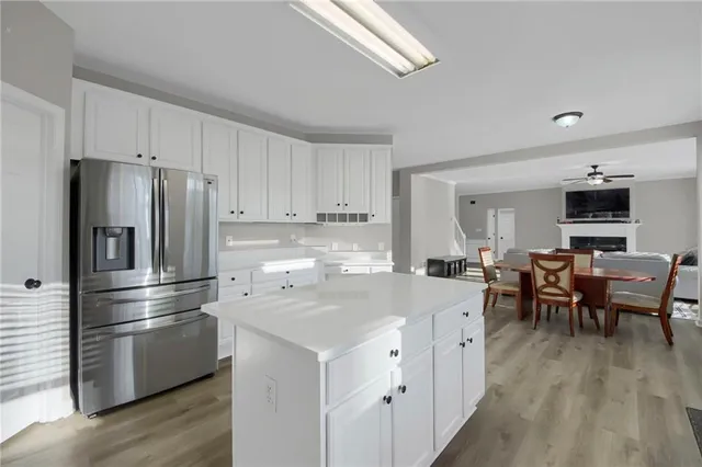 a kitchen with a refrigerator a stove top oven a sink dishwasher and white cabinets with wooden floor