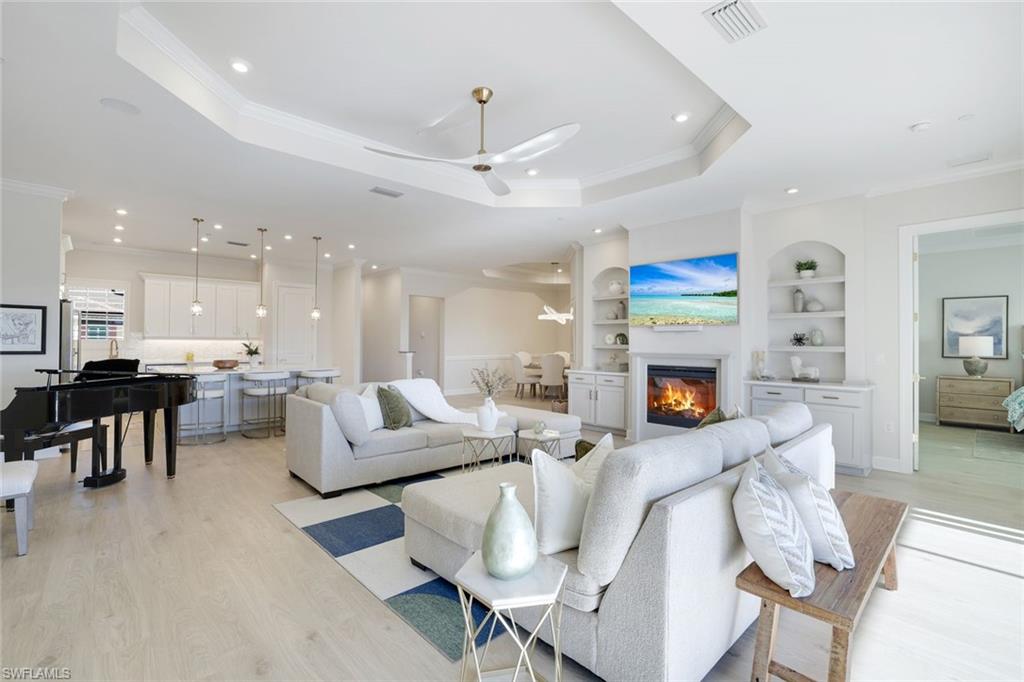 15336 Lucerna Street, Unit 203 Naples, FL 34114 - Photo 9 of 33 Living area with built in shelves, light wood-type flooring, ornamental molding, ceiling fan, and a tray ceiling
