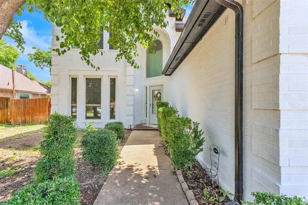 a view of a house with a small yard plants and large tree