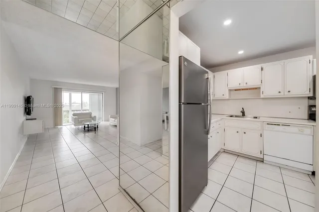 a kitchen with white cabinets a sink a stove a refrigerator and island