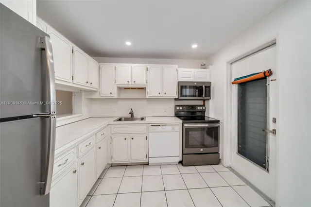 a kitchen with white cabinets stainless steel appliances and a sink