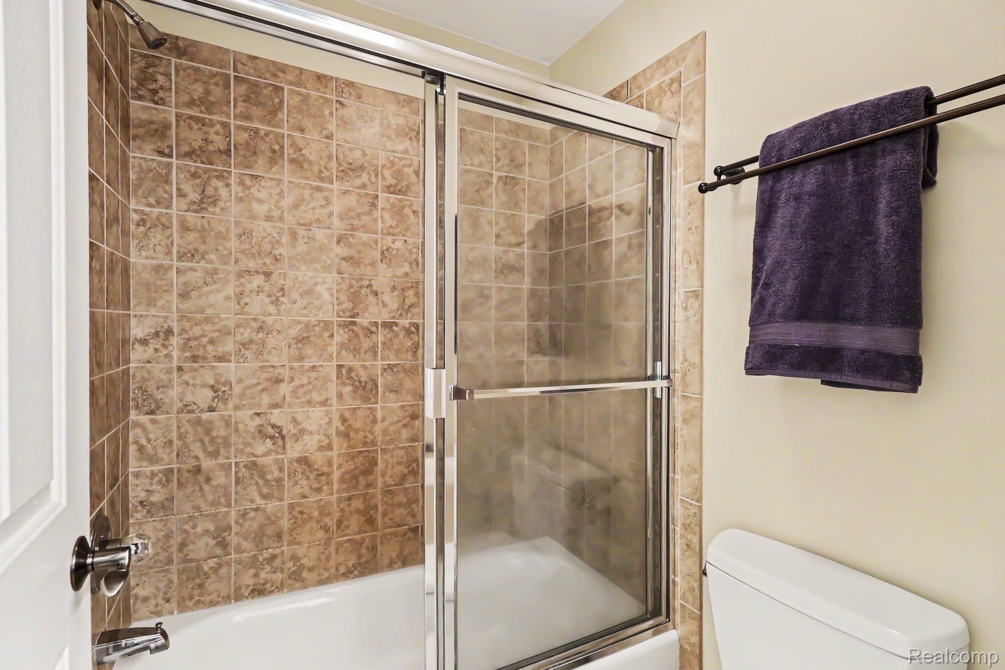 10490 Deer Ridge Trail Holly, MI 48442 - Photo 34 of 56 Bathtub with glass sliding doors, featuring a tiled surround and a built-in shower bench