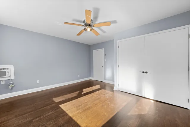 an empty room with wooden floor fan and windows
