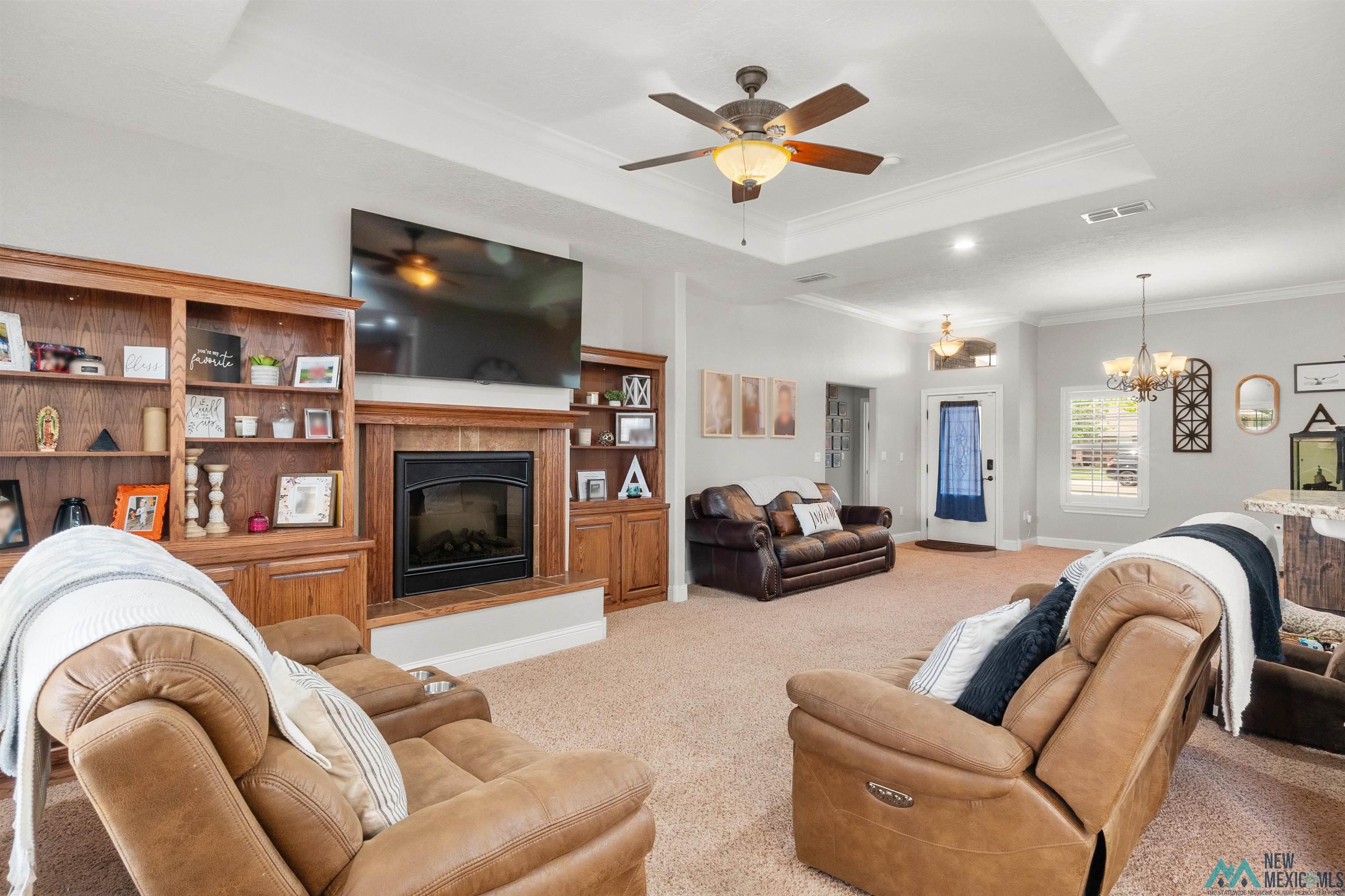 3913 Woodlark Road Clovis, NM 88101 - Photo 5 of 28 Spacious living area featuring a fireplace with built-in wooden shelving, a tray ceiling, recessed lighting, and a ceiling fan