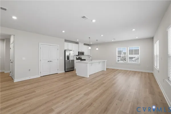 a large white kitchen with stainless steel appliances granite countertop a stove a refrigerator a oven and white cabinets with wooden floor