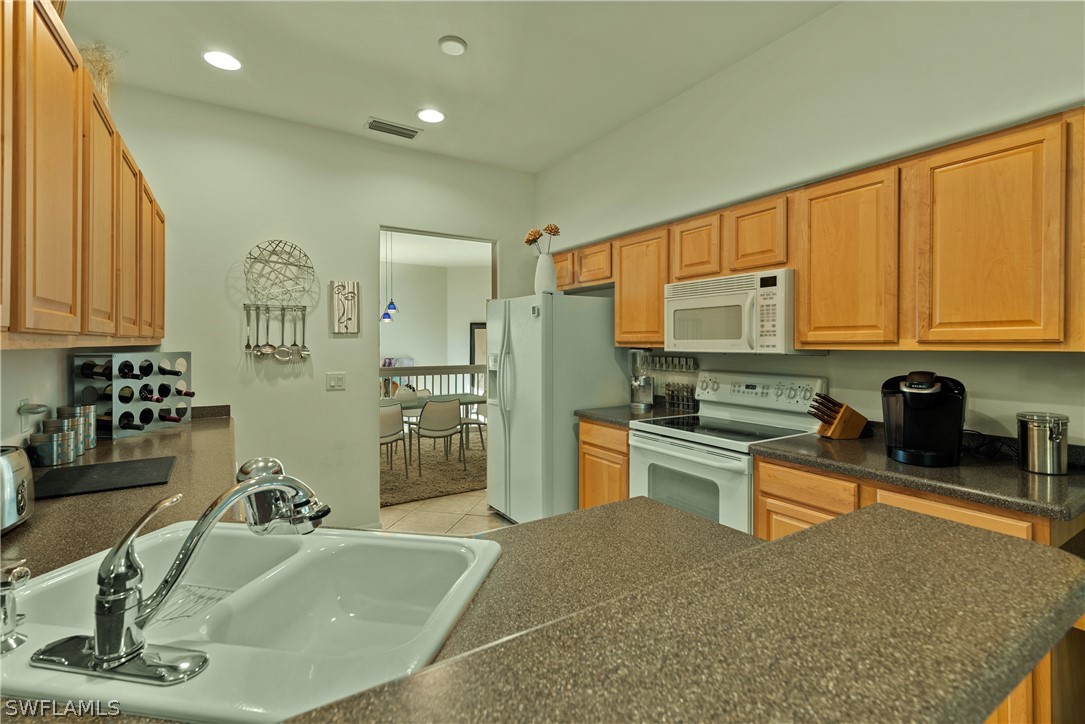 10013 Sky View Way, Unit 1705 Fort Myers, FL 33913 - Photo 4 of 24 a kitchen with stainless steel appliances granite countertop a sink and a refrigerator