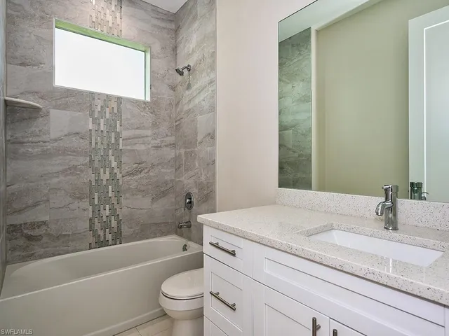 a bathroom with a granite countertop sink a toilet and bathtub
