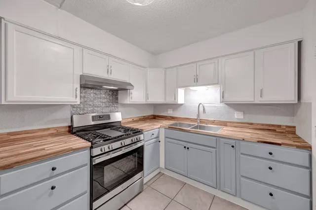 a kitchen with granite countertop white cabinets and stainless steel appliances