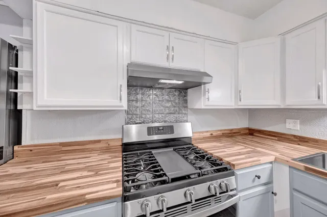 a kitchen with granite countertop a stove and a white cabinets