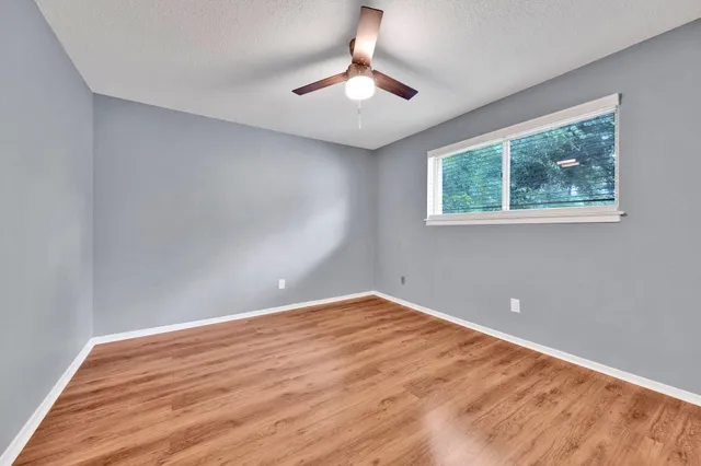 a view of an empty room with window and wooden floor
