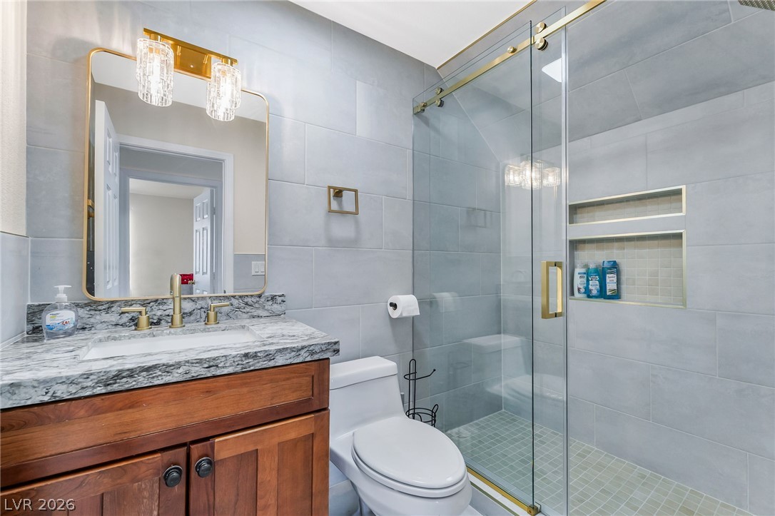 104 Appian Way Henderson, NV 89002 - Photo 13 of 24 A refined bathroom featuring a contemporary vanity, framed mirror, and a sleek glass-enclosed shower.