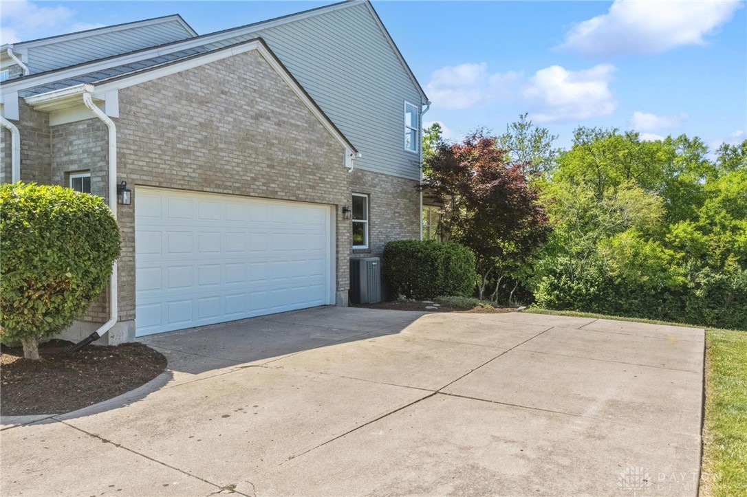 70 Martin Lane Springboro, OH 45066 - Photo 54 of 69 This residence features a spacious garage and ample driveway space, complemented by lush surrounding greenery.