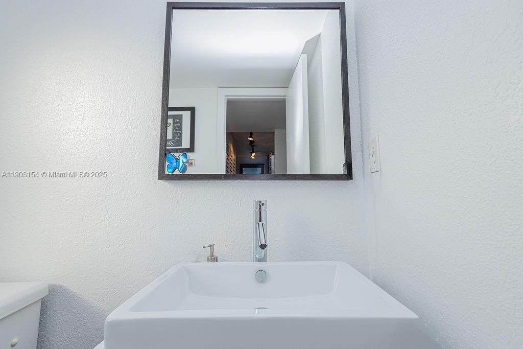 3450 Blue Lake Drive, Unit 305 Pompano Beach, FL 33064 - Photo 47 of 66 a bathroom with a sink and mirror