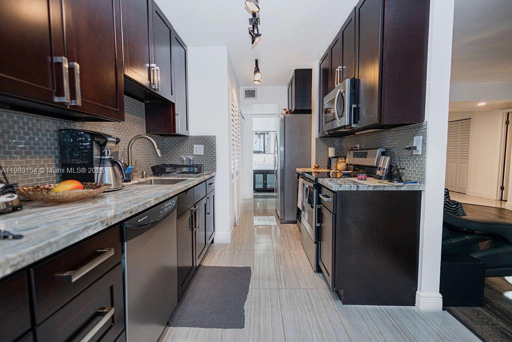 3450 Blue Lake Drive, Unit 305 Pompano Beach, FL 33064 - Photo 52 of 66 a kitchen with stainless steel appliances granite countertop a refrigerator a sink dishwasher a stove and a microwave oven on granite countertops