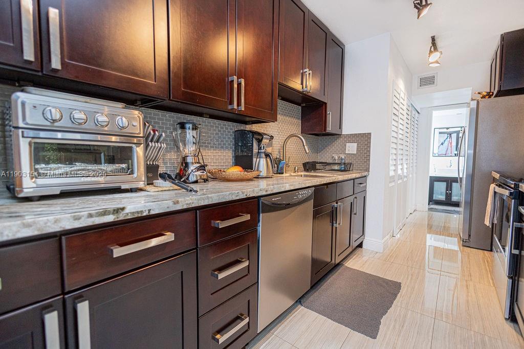 3450 Blue Lake Drive, Unit 305 Pompano Beach, FL 33064 - Photo 64 of 66 a kitchen with stainless steel appliances granite countertop a sink a stove microwave and cabinets