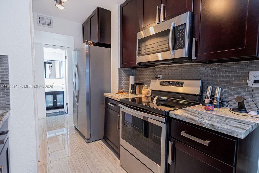 3450 Blue Lake Drive, Unit 305 Pompano Beach, FL 33064 - Photo 66 of 66 a kitchen with stainless steel appliances granite countertop a stove microwave and refrigerator
