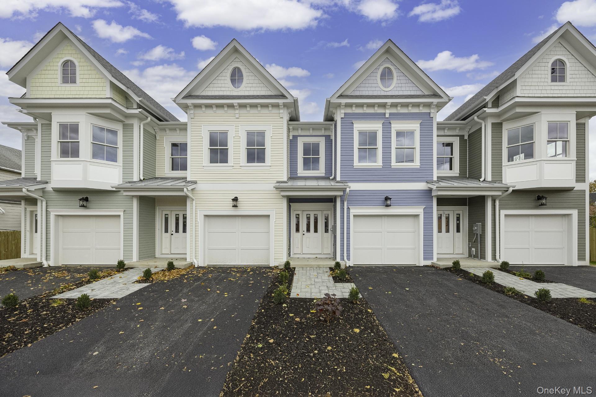 View of front facade featuring a standing seam roof, a metal roof, and asphalt driveway