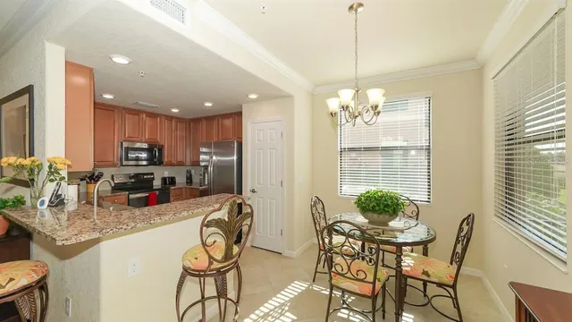 a kitchen area with stainless steel appliances kitchen island granite countertop a dining table and chairs