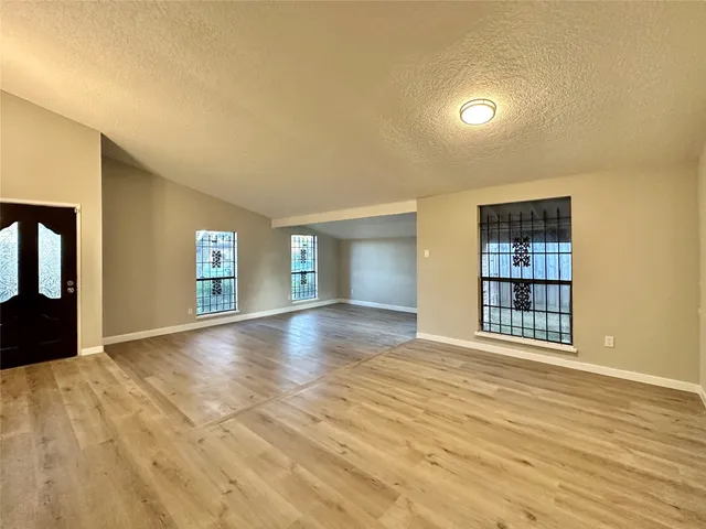 a view of an empty room with window and wooden floor