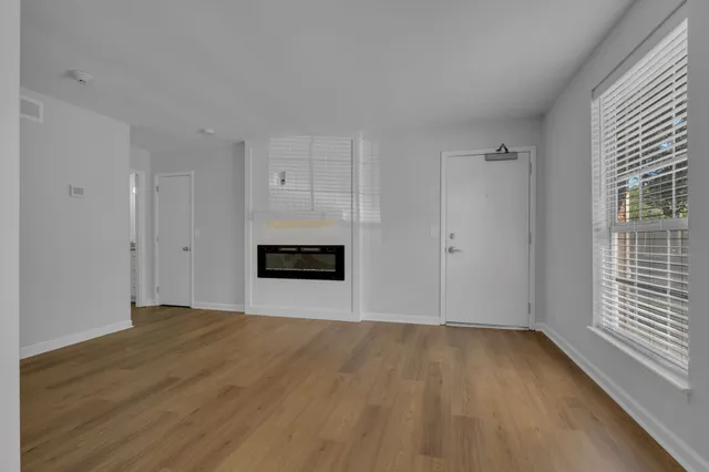 a view of empty room with wooden floor and fireplace